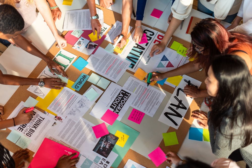 Jonge makers werken samen rond tafel met papieren en postits